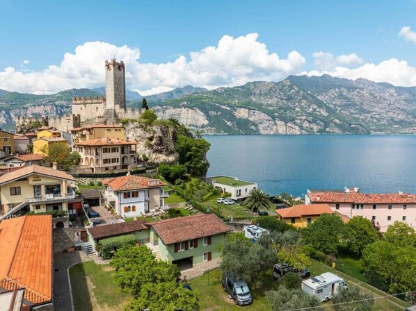 A coastal town with a prominent castle, residential buildings, and a lake. - Villaggio Turistico Priori Malcesine (Malcesine)
