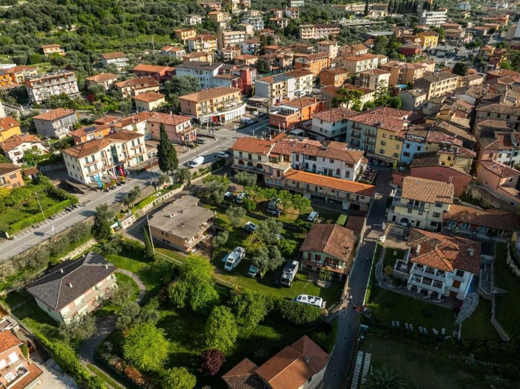 An aerial view of a residential area with closely packed houses, narrow streets, and green spaces.