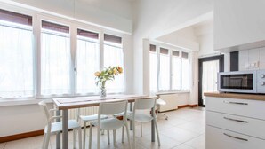 A bright kitchen with white cabinets, a microwave, and a dining area with a table and chairs. - Villaggio Turistico Priori Malcesine (Malcesine)