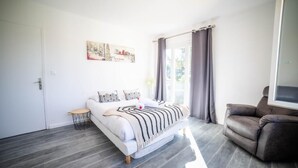 A modern bedroom with a bed, a sofa, a small table, and a painting on the wall. - Villa CosyFamily-Pool-15MinPlage-Wifi-Family (Pérols)