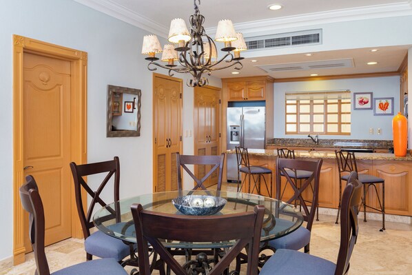 A dining area with a glass table, wooden chairs, and a chandelier. - Beachside Escape at Riviera Nayarit w Pool (Nuevo Nayarit)