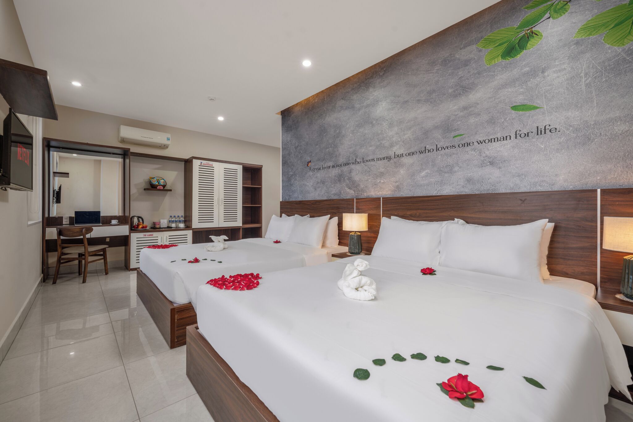 Ein Hotelzimmer mit zwei Betten, einem Schreibtisch, einem Stuhl und einem Badezimmer.