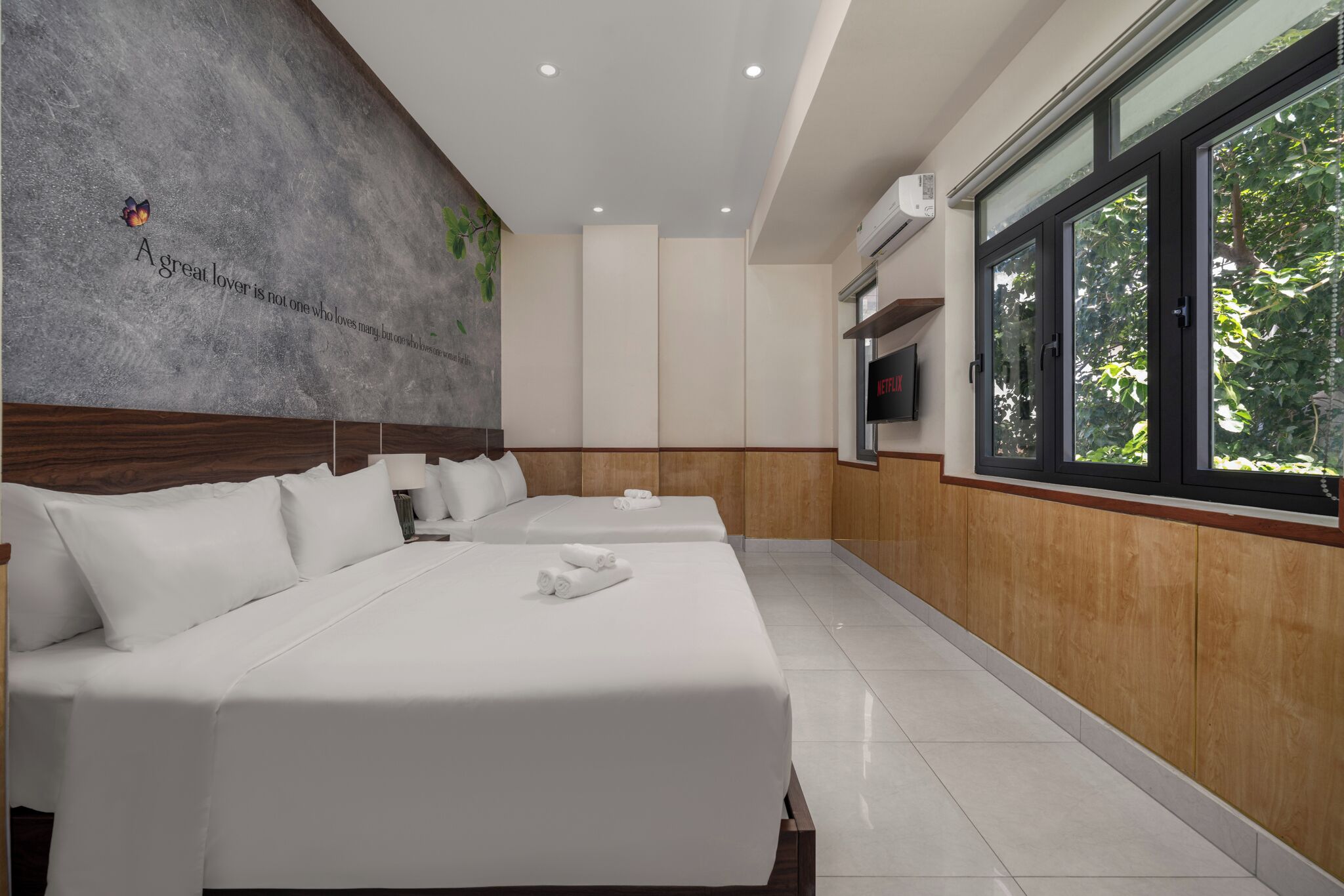 Une chambre d’hôtel avec deux lits, une grande fenêtre et un climatiseur fixé au mur.