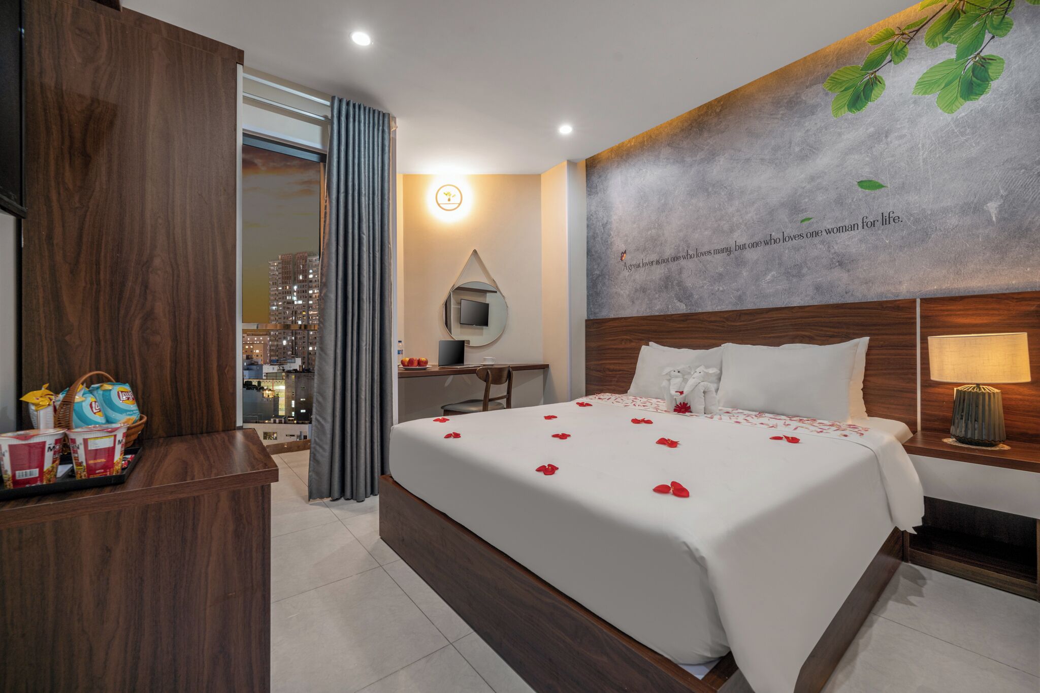 A hotel room with a large bed, a desk, a TV, and a city view.