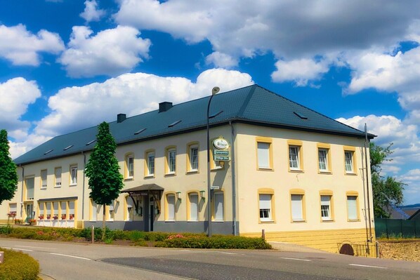 Ein zweistöckiges Gebäude mit symmetrischer Fassade, zahlreichen Fenstern und einem zentralen Eingang.