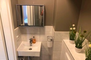 Ein Badezimmer mit Waschbecken, Spiegel, Toilette und einem kleinen Topfpflanzen.