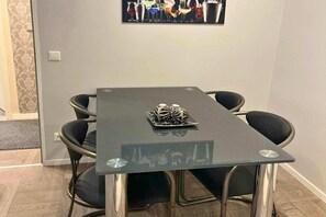 A modern dining area with a glass-top table, black chairs, and a decorative centerpiece.