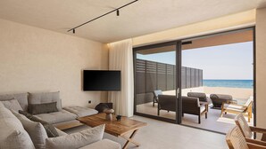 A modern living room with a flat-screen TV, grey sofas, a wooden coffee table, and a view of the sea through large glass doors. - Onora Villa, Steps from the Sea by etouri (Chania)