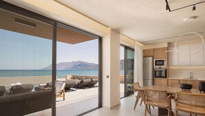 A modern kitchen with a view of the sea, a dining area with wicker chairs, and a balcony with lounge chairs. - Onora Villa, Steps from the Sea by etouri (Chania)
