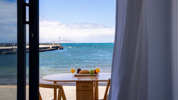 A table with breakfast items and a view of the sea.