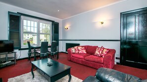 A living room with a red sofa, black leather couch, and a dining area with a table and chairs. - Cosy & Central 2Bd Apartment Milngavie, Glasgow (Glasgow)