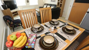 A dining table set with bowls, plates, cutlery, and a fruit basket.