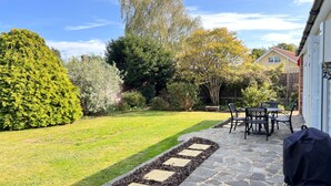 A patio with stone flooring, a lawn, and a seating area with chairs and a table.