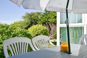 A table with chairs and a table umbrella in a garden area. - Amazing Beachside 2Bd Family Home With Garden (Margate)