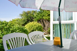 Una mesa con sillas y una sombrilla en un jardín.