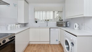 Una cocina moderna con armarios blancos, lavavajillas, microondas y estufa.