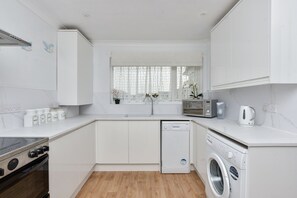 A modern kitchen with white cabinetry, a dishwasher, a microwave, and a stove. - Amazing Beachside 2Bd Family Home With Garden (Margate)