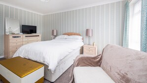 A bedroom with a bed, bedside tables, a TV, a dresser, and a window with curtains. - Amazing Beachside 2Bd Family Home With Garden (Margate)