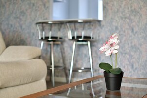 Una sala de estar moderna con un sofá, una mesa de centro de vidrio y una orquídea en maceta.