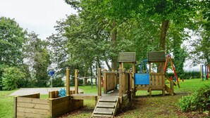 A wooden playground structure with a slide, climbing area, and a small bridge. - Special 2 Bedroom Home In White Cross (Newquay)