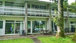 A two-story building with large windows and a balcony. - Special 2 Bedroom Home In White Cross (Newquay)