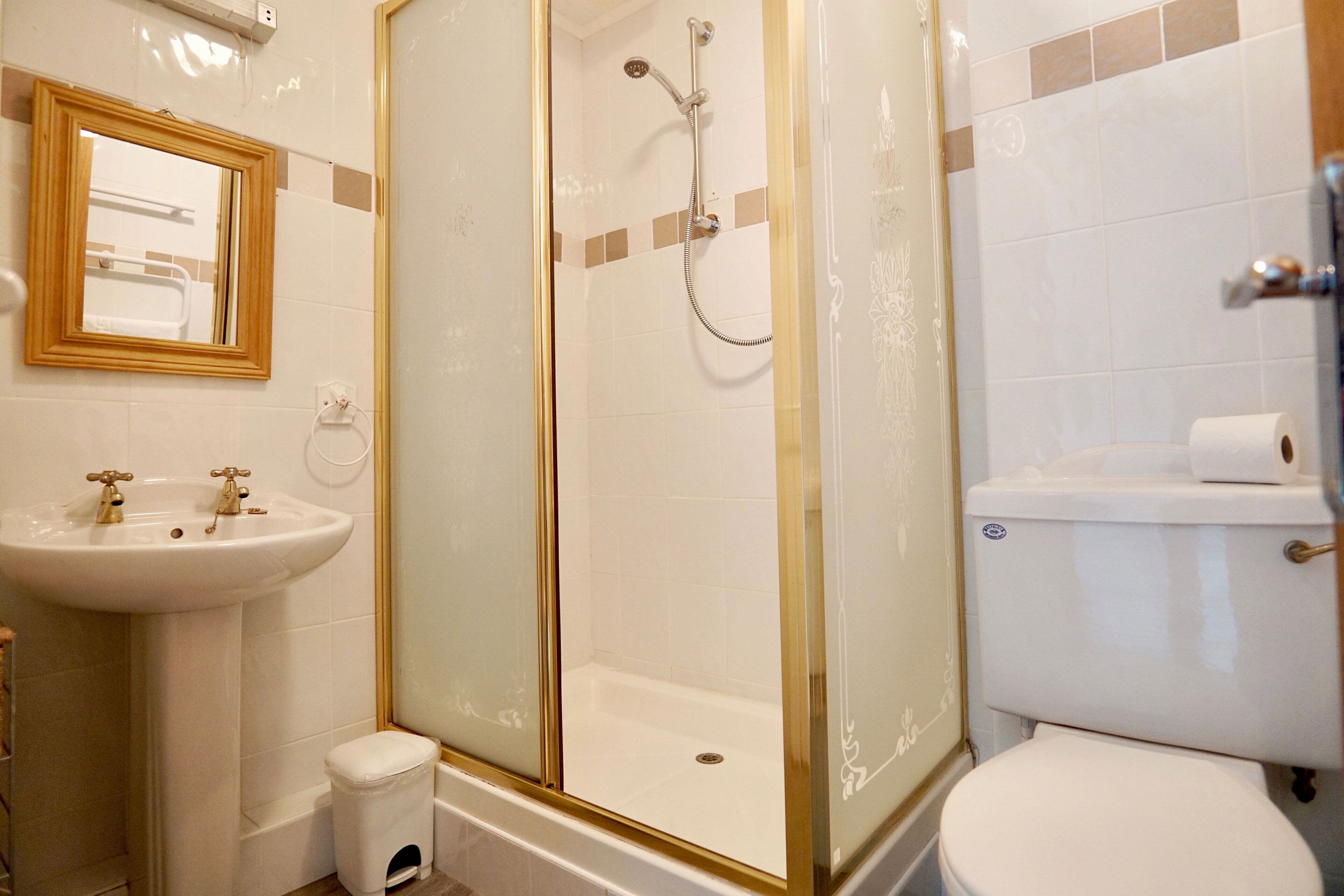 A bathroom with a glass-enclosed shower, a sink, and a toilet.