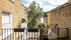 A narrow alleyway with brick buildings, a metal gate, and potted plants.