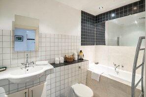Ein Badezimmer mit zwei Waschbecken, einer Toilette, einer Badewanne und einem Spiegel.