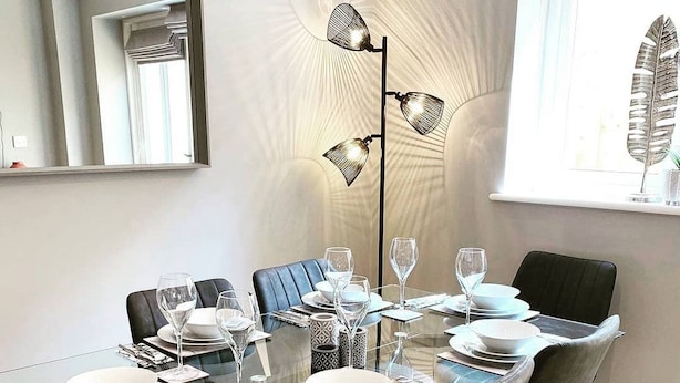 A modern dining area with a glass table, black chairs, and a floor lamp. - Elegant Ludlow Haven: 4Bed Ultimate Tranquility (Ludlow)