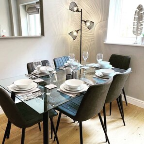 Un comedor moderno con una mesa de vidrio, sillas negras y una lámpara de pie.