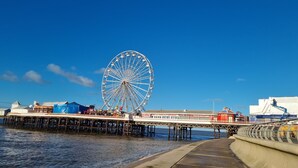 Un muelle con una noria grande, un paseo marítimo y un edificio con señalización.