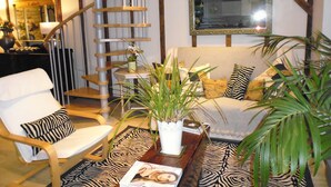 A living room with a sofa, armchair, and a wooden spiral staircase. - Wonderful Picturesque Countryside Cottage (Banbury)