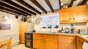 Une cuisine avec des meubles de rangement en bois, une cuisinière et une fenêtre.