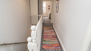 A staircase with a white railing and a colorful woven carpet. - Little Boat: A Modern Beachside Flat (Bournemouth)