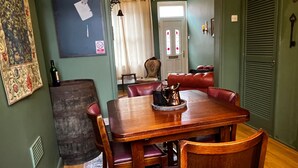 A dining area with a wooden table and leather chairs, a decorative pitcher, and a bottle of wine on the table. - Robin’S Hollow: 2Bd Home Near Wrexham Afc (Wrexham)