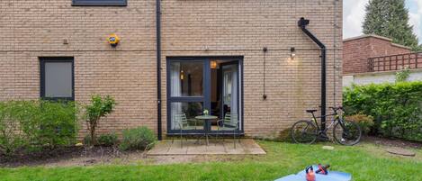 A brick building with a patio, a bicycle, and a blue mat with exercise equipment.
