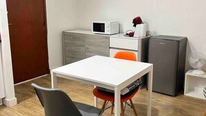 A small, modern kitchen with a microwave, refrigerator, and a dining area with a table and chairs.