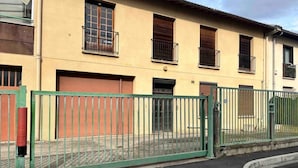 A building with a gated entrance, a red garage door, and a green metal fence.