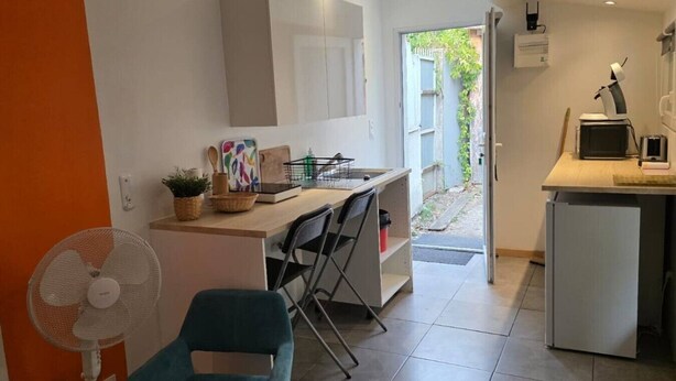 A modern kitchen with a dining area, a fan, and a small refrigerator. - Studio on Metro Line B at La Vache (Toulouse)