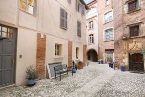 A narrow cobblestone alley with a bench, potted plants, and a door on the left.