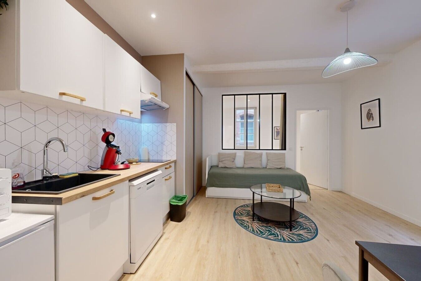 Un espace de vie compact comprenant un coin cuisine, un espace repas et un lit.