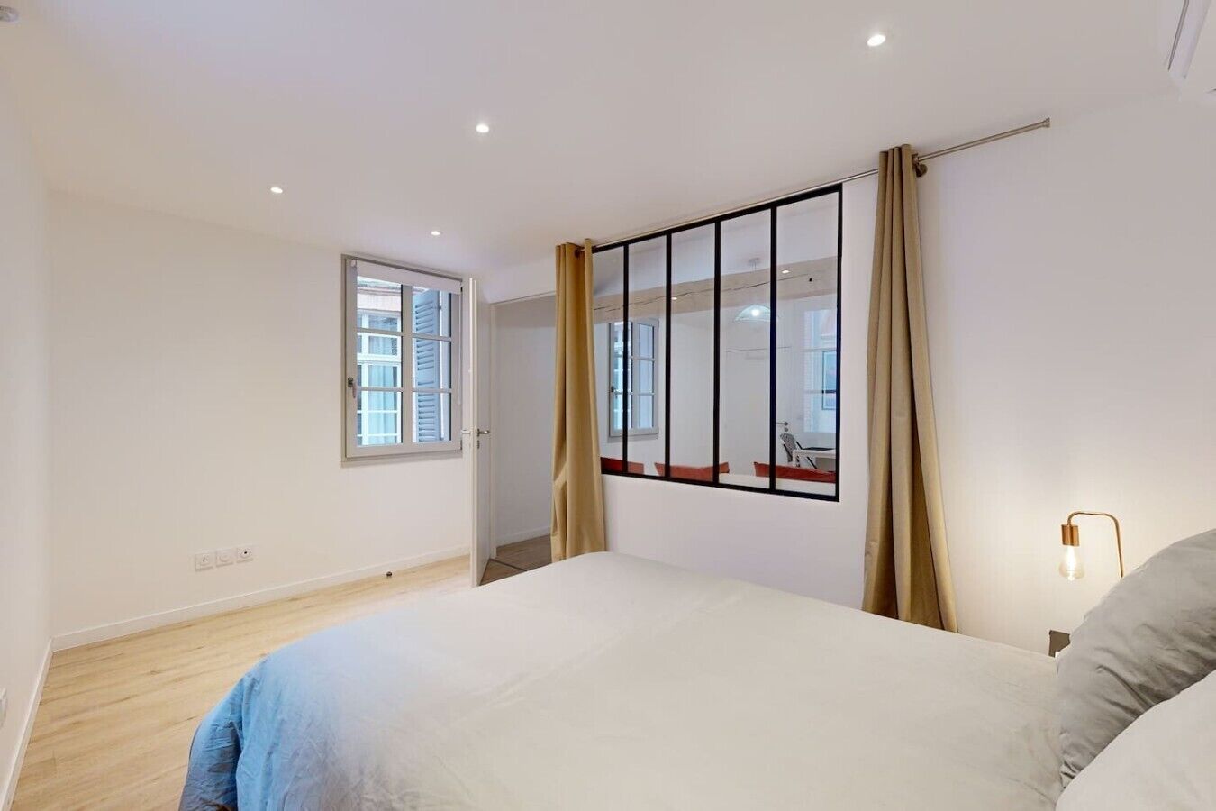 Une chambre à coucher avec un lit, une fenêtre, une porte et un luminaire.