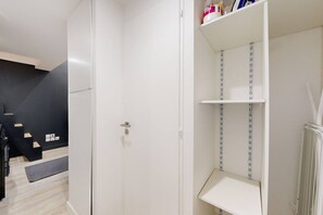 Une pièce avec une porte blanche, un mur noir, un escalier en bois et une étagère blanche avec un radiateur.