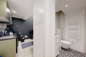 Une cuisine compacte dotée d’appareils électroménagers modernes, un coin repas et une petite salle de bain avec des toilettes et une fenêtre.
