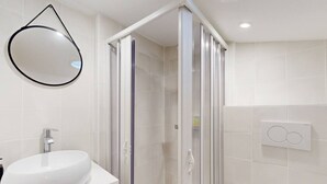 A bathroom with a white sink, a glass-enclosed shower, and a wall-mounted mirror.