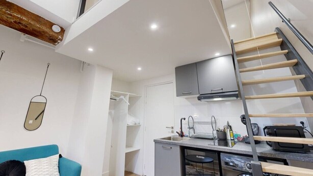 A compact living space with a kitchenette, a dining area, and a staircase.