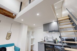 A compact living space with a kitchenette, a dining area, and a staircase.