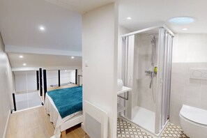 A bedroom with a bed, a shower, and a toilet.