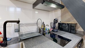 A kitchen with a stainless steel sink, a dish rack, a coffee machine, and a microwave.