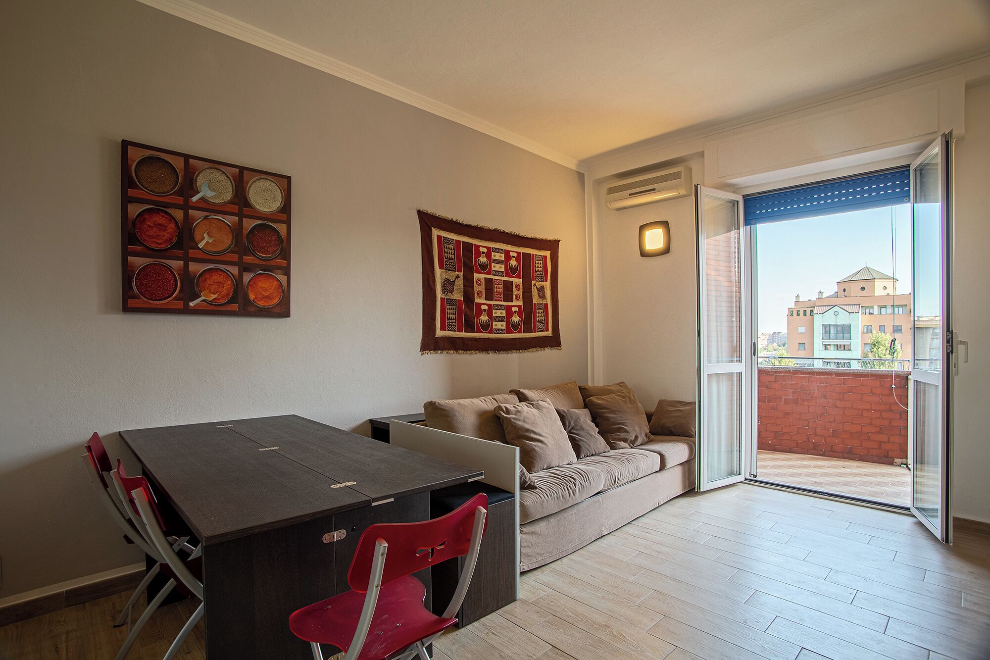 A living room with a sofa, a dining table with chairs, and a sliding glass door leading to an outdoor area.